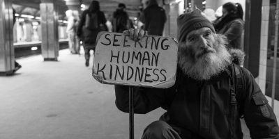 man holding card with seeking human kindness text